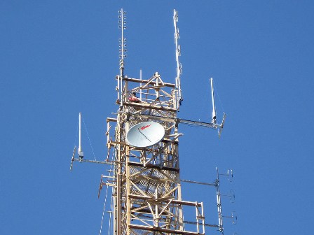 Two automatic dependent surveillance broadcast (ADS-B) antennas (short, white with three guide wires) atop a communications tower located on the Nullabor Plain.